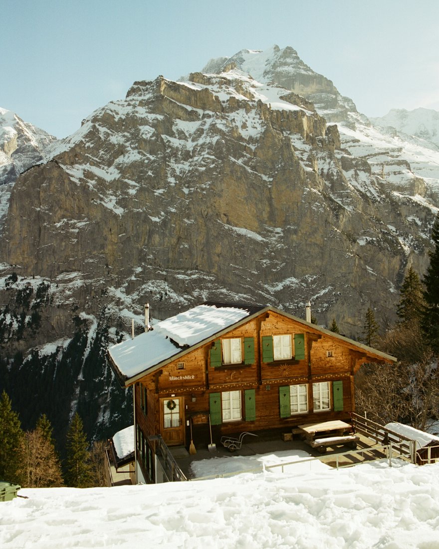 Un chalet en bois au pied de sommets enneigés