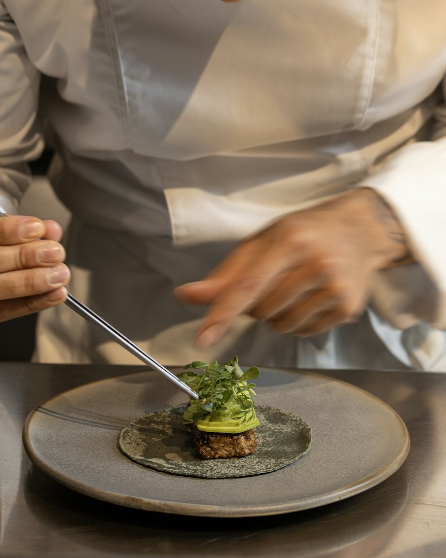 Un chef dressant une assiette à la pince